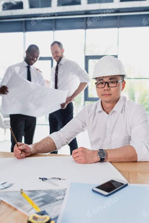 Preview: professional architects in formal wear working with blueprints at modern office, businessmen group