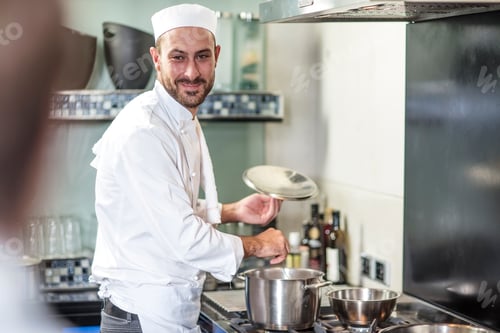 Preview: Portrait of chef seasoning pan on stove