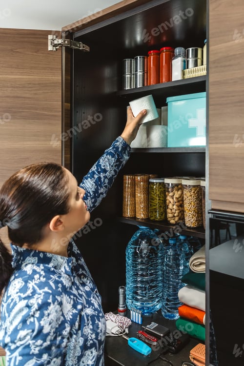 Preview: Portrait of woman organizing emergency food pantry in kitchen. 72 hours survival kit concept.