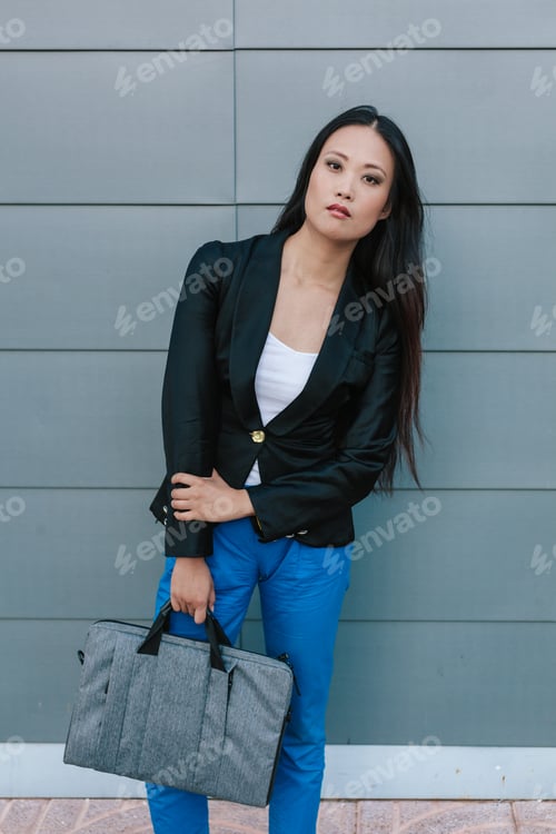 Preview: Ethnic businesswoman walking along street near building
