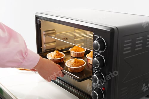 Preview: Woman's hands taking buscuit cupcakes out of mini oven