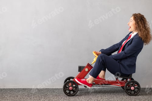 Preview: Successfull businesswoman driving toy car outdoor