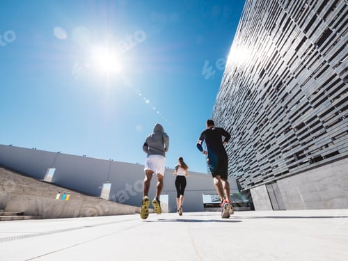 Preview: three friends athletes jogging in a modern building district