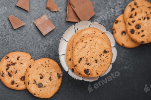 Preview: Freshly baked chocolate chip cookies in a decorative bowl on a dark background