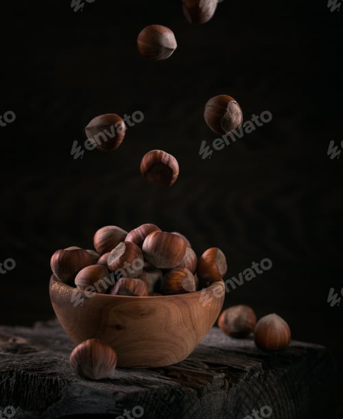 Preview: Pile of hazelnuts filbert in a wooden bowl on a dark wooden background