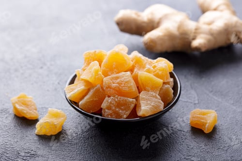 Preview: Candied Ginger in Black Bowl on Dark Stone Background. Close up. Copy Space.