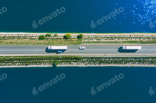 Preview: Aerial drone view of freight transporter semi-trucks and cars driving on bridge road over blue sea