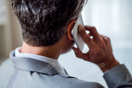 Preview: A rear view of mature businessman with smartphone making a phone call.