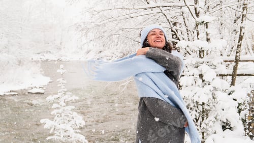 Preview: Woman enjoys winter joyfully while wrapped in a blue scarf amidst snowy nature