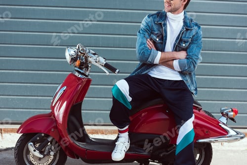 Preview: cropped shot of man in stylish old school clothes on vintage red scooter
