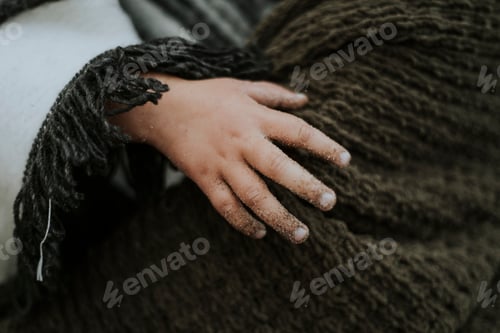 Preview: Child's Hand on Brown Textile with Fringe