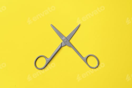 Preview: Gray scissors on yellow background top view
