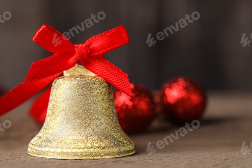 Preview: Bell with red bow on wooden table, closeup and space for text. Christmas decor