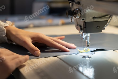 Preview: Closeup of female tailor work on sewing machine stitch fabric patterns for clothes. Garment industry