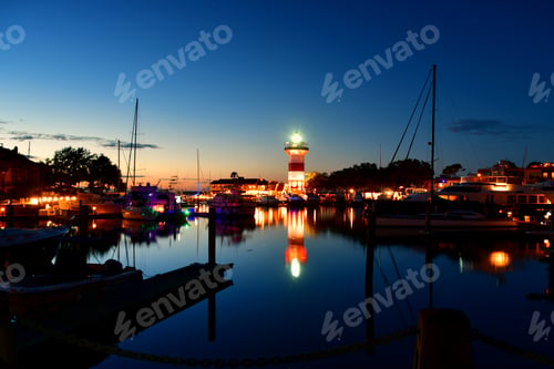 Preview: Lighthouse and marina with boats, ships and yachts at sunset dusk