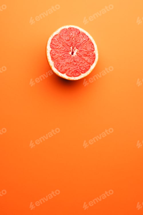 Preview: Close up of half of red grapefruit and copy space on orange background