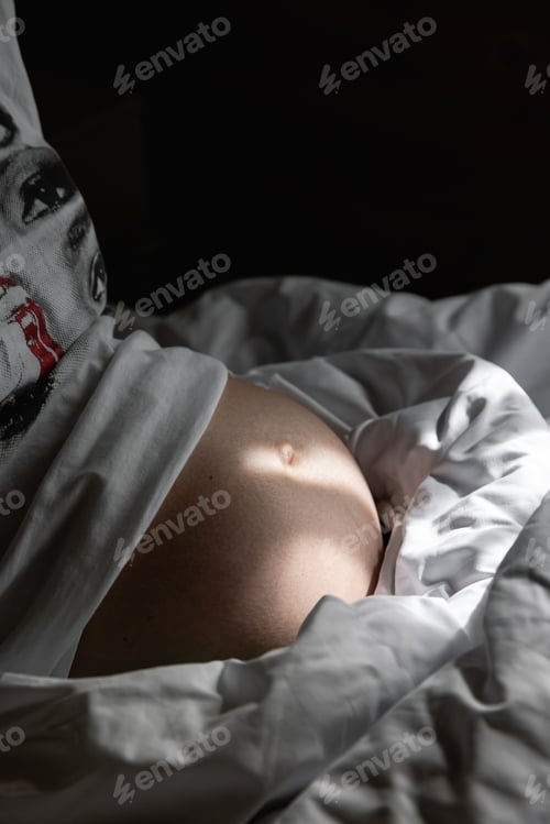 Preview: belly of a pregnant girl illuminated by the morning rays of the sun