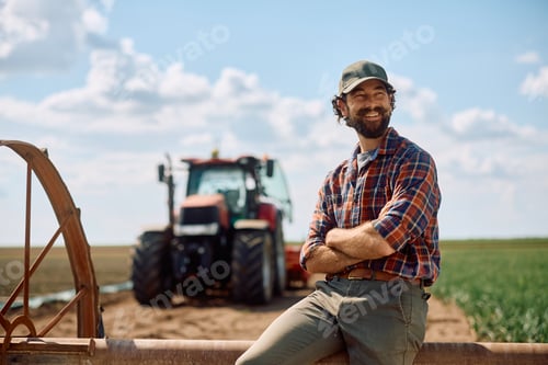 Preview: Proud farmer with crossed arms in the field looking away.