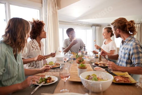 Preview: A group of millennial friends sitting at a table, eating lunch and talking, backlit