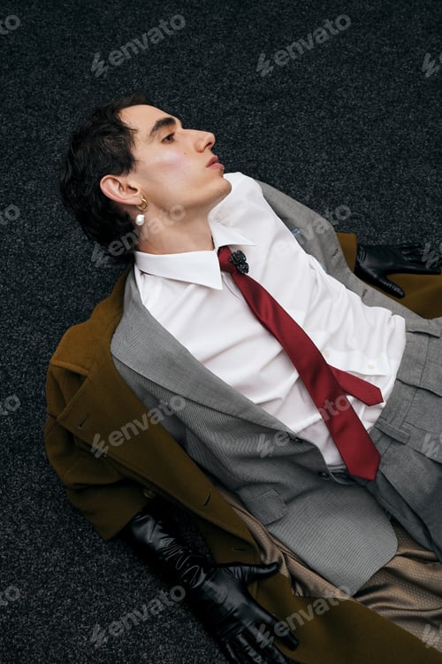 Preview: Stylish man poses elegantly on the floor in a modern, artistic fashion setting