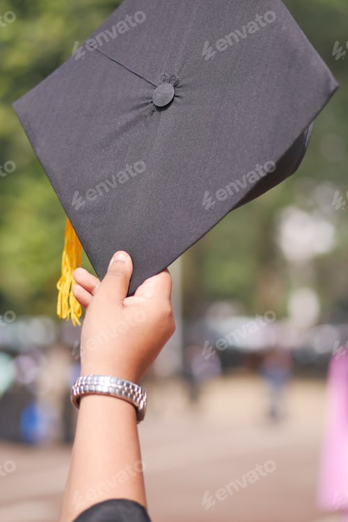 Preview: Student hold hats in hand during commencement success on yellow background