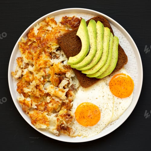 Preview: Tasty Homemade Fried Hashbrowns and Eggs on a plate on a black background, top view.
