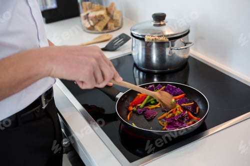 Preview: Mid-section of a man preparing food in kitchen