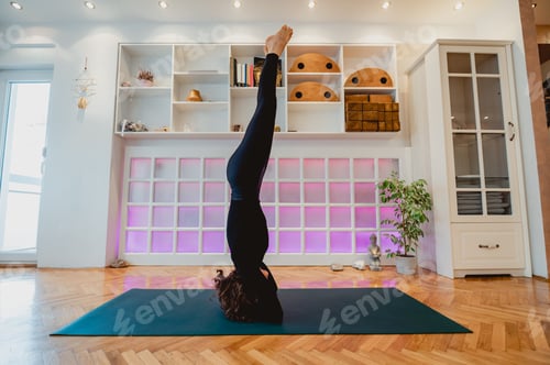 Preview: Dark haired girl doing headstand yoga pose while balancing and breathing.