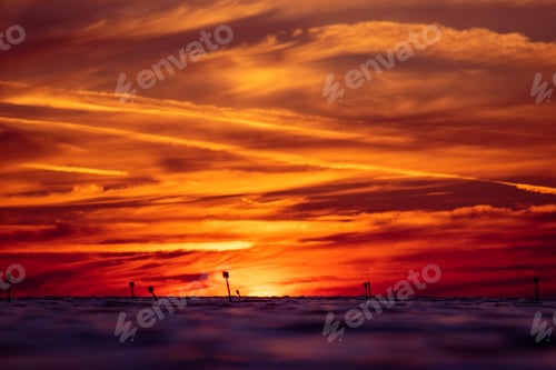 Preview: Orange and yellow sunset over the ocean with cloudy skies