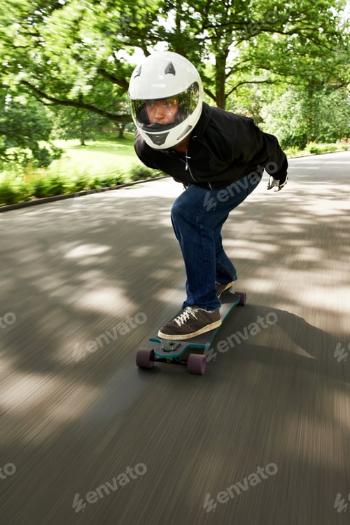 Preview: Building up speed. Shot of a man skateboarding down a lane at high speed on his board.