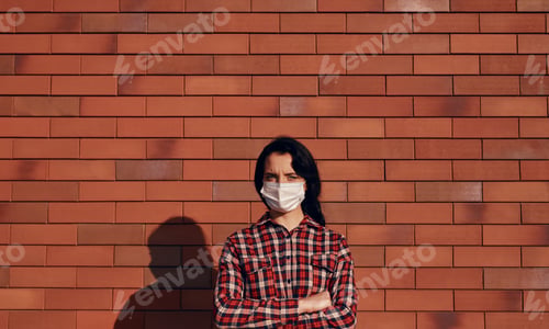 Preview: Confident woman in mask against brick wall