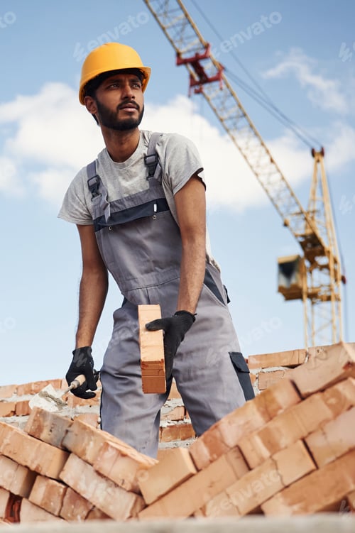 Preview: Working against blue sky. Handsome Indian man is on the construction site