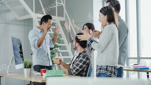 Preview: Asian creative businessman and his colleagues arms raised celebrating success .
