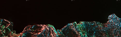 Preview: panoramic shot of torn foil with colorful lighting reflection in darkness isolated on black