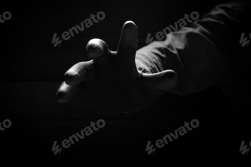 Preview: Scary hand of mysterious criminal in black glove reaching from the dark background in low key style