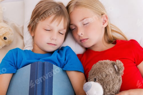 Preview: Tired after active day. Top view of two cute children sleeping while lying in bed together