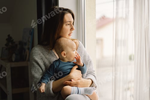 Preview: Woman Holding Baby Near Bright Window Indoors