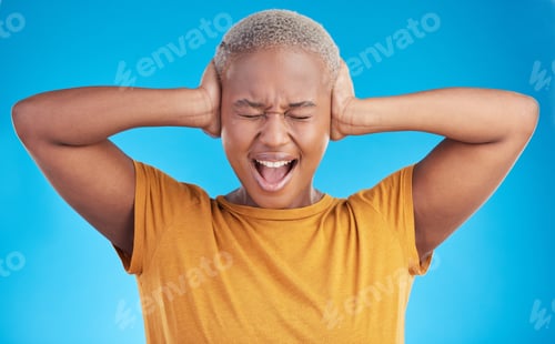Preview: Headache, hands on ears and black woman shout in studio isolated on a blue background. Stress, nois