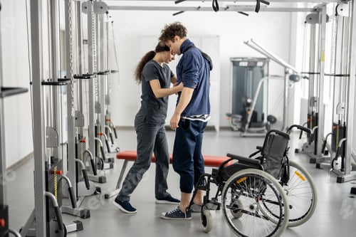 Preview: Rehabilitation specialist helps a guy stand out of a wheelchair
