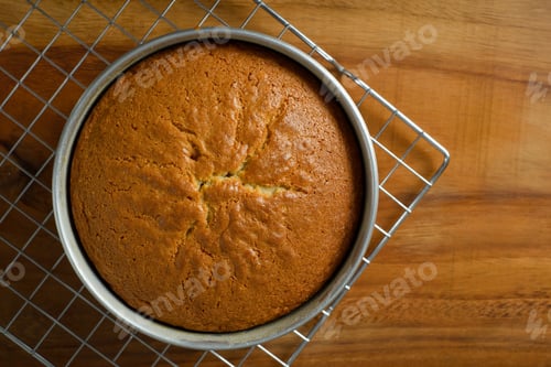Preview: Freshly baked sponge cake cooling on wooden table.