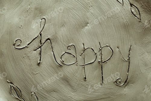 Preview: Potter inscription happy on a wet clay plate. Grey modelling clay background and texture