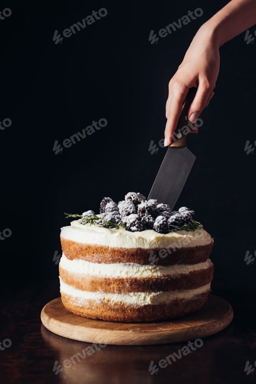 Preview: cropped shot of woman cutting delicious blackberry cake on black