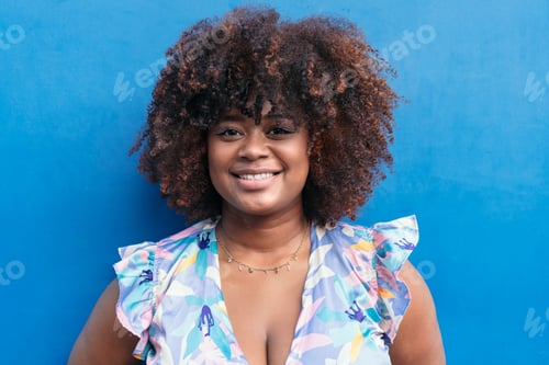 Preview: portrait of a beautiful young African girl smiling with blue background.