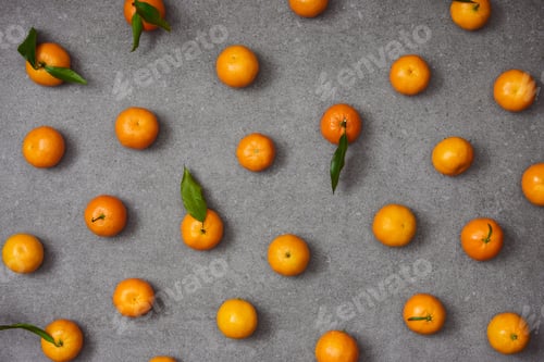 Preview: flat lay of sweet tangerines with green leaves on grey table