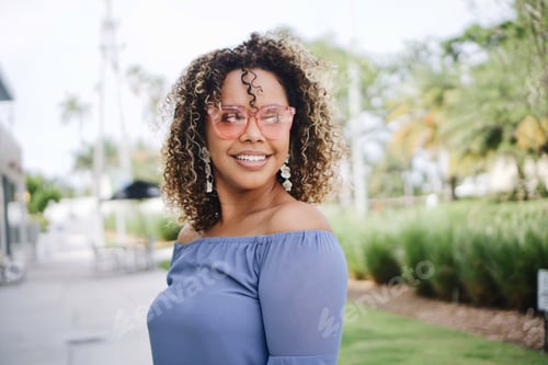 Visualização: Jovem mulher com cabelos encaracolados e óculos no verão