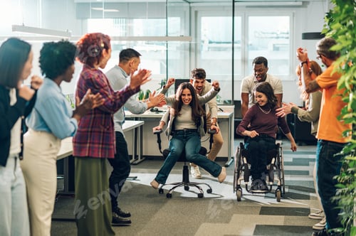 Preview: Multiracial business team having fun while racing on office chairs