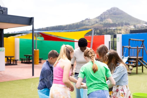 Preview: Diverse female teacher and pupils collecting rubbish for recycling in schoolyard, with copy space
