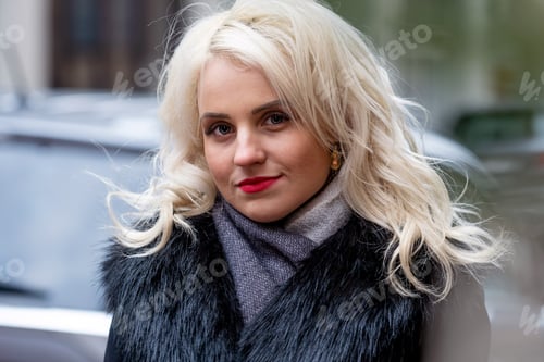 Preview: Portrait of a young smiling blonde woman on defocused street background. Copy space.
