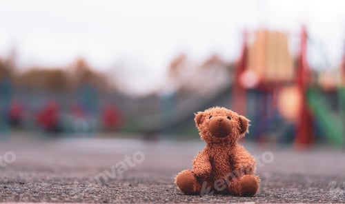 Preview: Lost teddy bear toy lying on playground floor in gloomy day,Lonely and sad brown bear doll