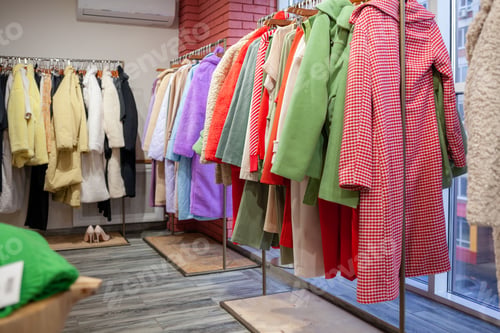 Preview: Colorful women's dresses on hangers in a retail shop.